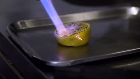 chef roasts lemon on a metal plate