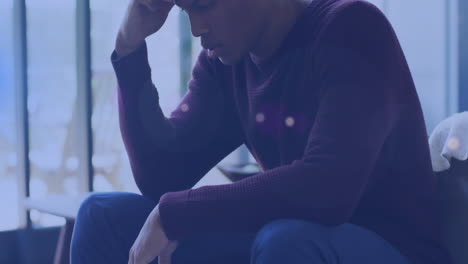 animation of glowing lights of water over a sad african american man