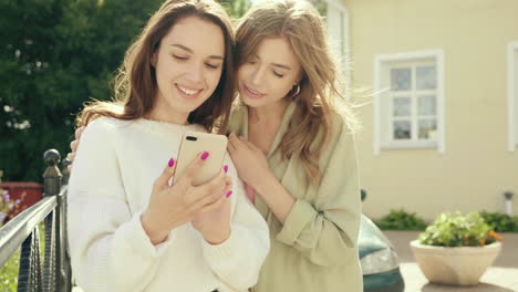 dos mujeres mirando un teléfono móvil al aire libre