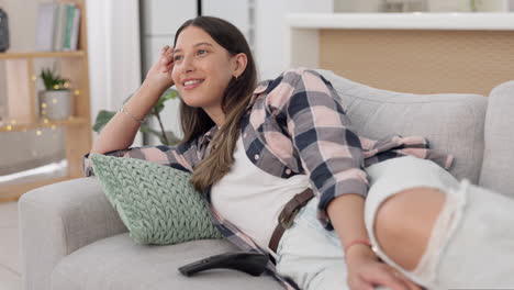 mujer, riendo y viendo televisión en el sofá