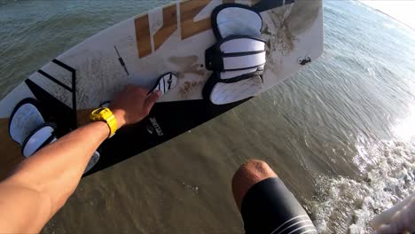 hombre pobre recoge la tabla de kitesurf arena corre en el agua salto día de verano soleado