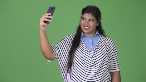young overweight beautiful indian businesswoman against green background