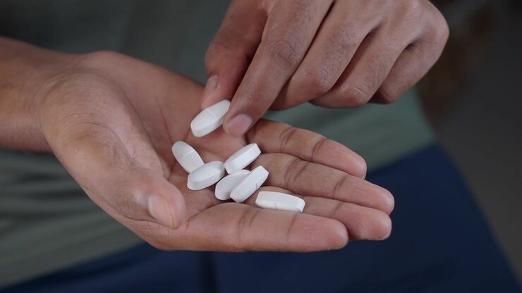Person's Hand Holding White Pills and Taking One