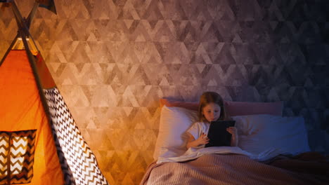 addicted kid plays video game on tablet in bedroom