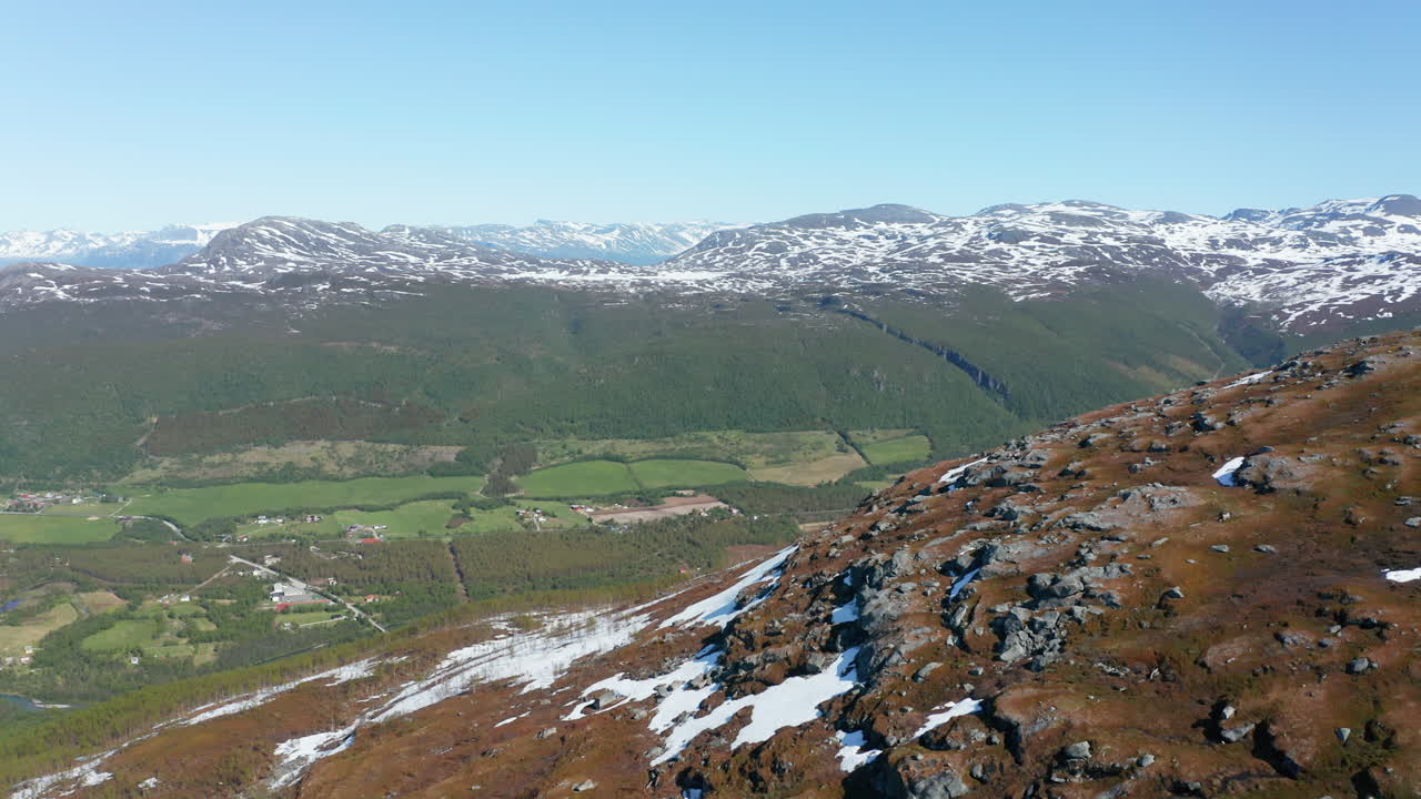 vista aérea sobre la cima de una montaña, hacia un pueblo y un valle, soleado, día de verano, en rotsund, nordland, noruega - dolly, pan, drone shot