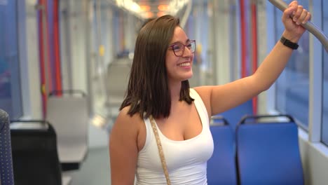 mujer sonriendo en el autobús sosteniendo un agarre de mano para la seguridad mientras viaja en un medio de transporte en tren