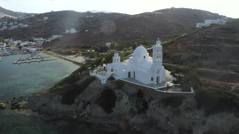 circling drone aerial shot of white church in the port of ios, greece near chora