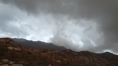 overcast clouds over forested mountains at misty morning