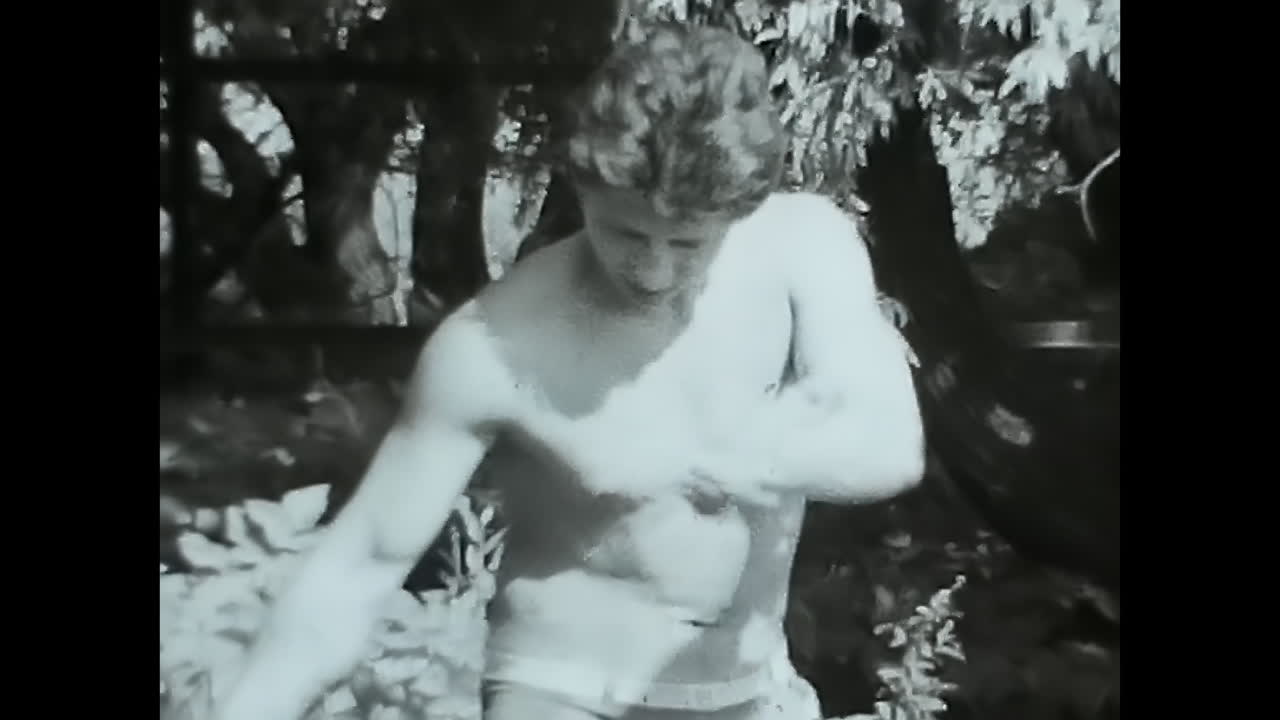 Vintage Video of Man Operating a Lawn Mower in Soviet Union. CIRCA USSR 1980s: An old black and white video capturing a man proficiently handling a lawn mower in the Soviet Union.