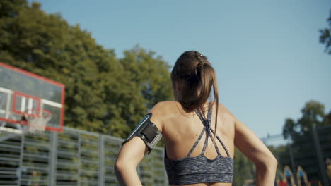 rear view of a sporty woman warming up and stretching at outdoor basketball court on a summer morning 1