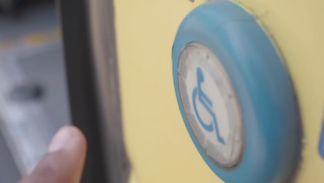 a finger pushing the button on a door for people with disabilities