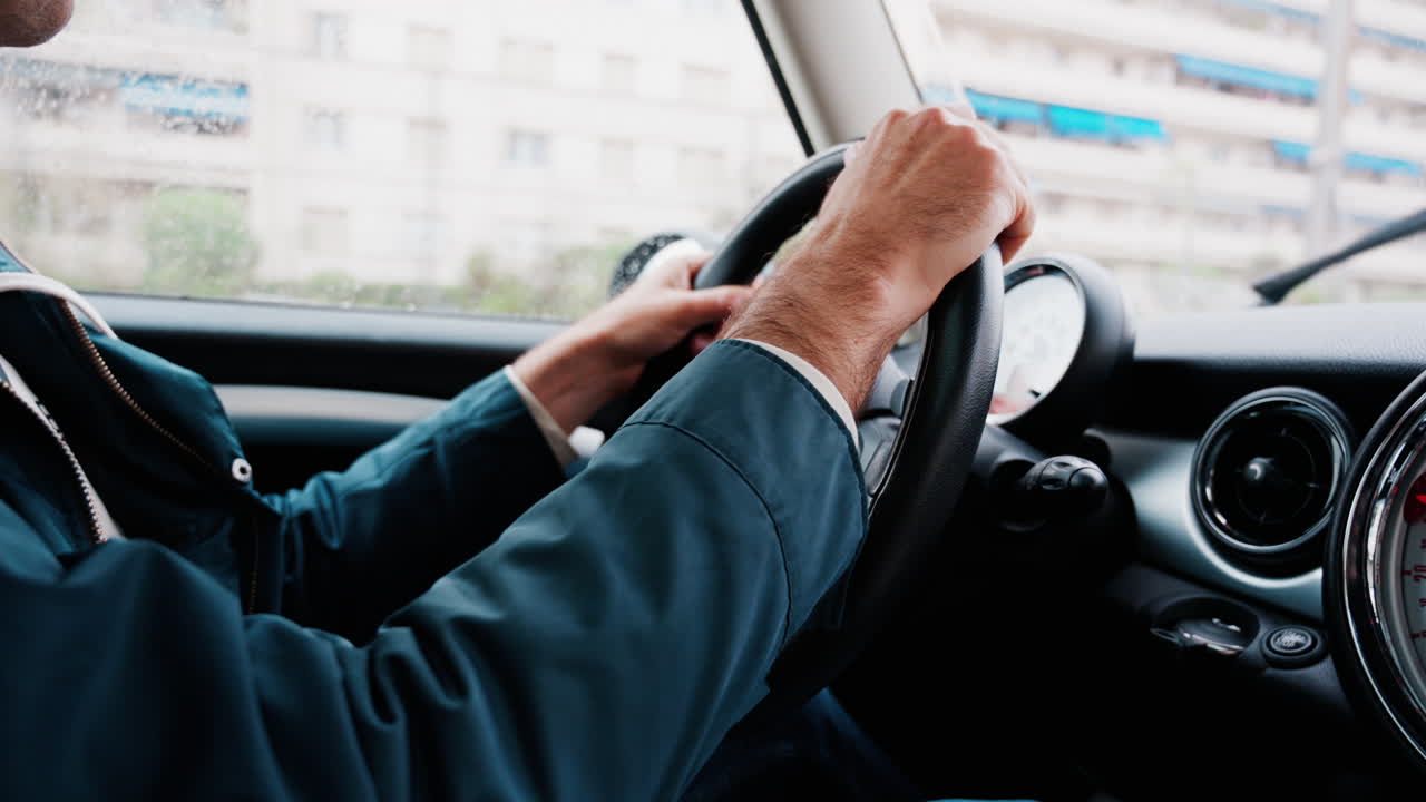 Close up of a man driving a car on the road in the rain