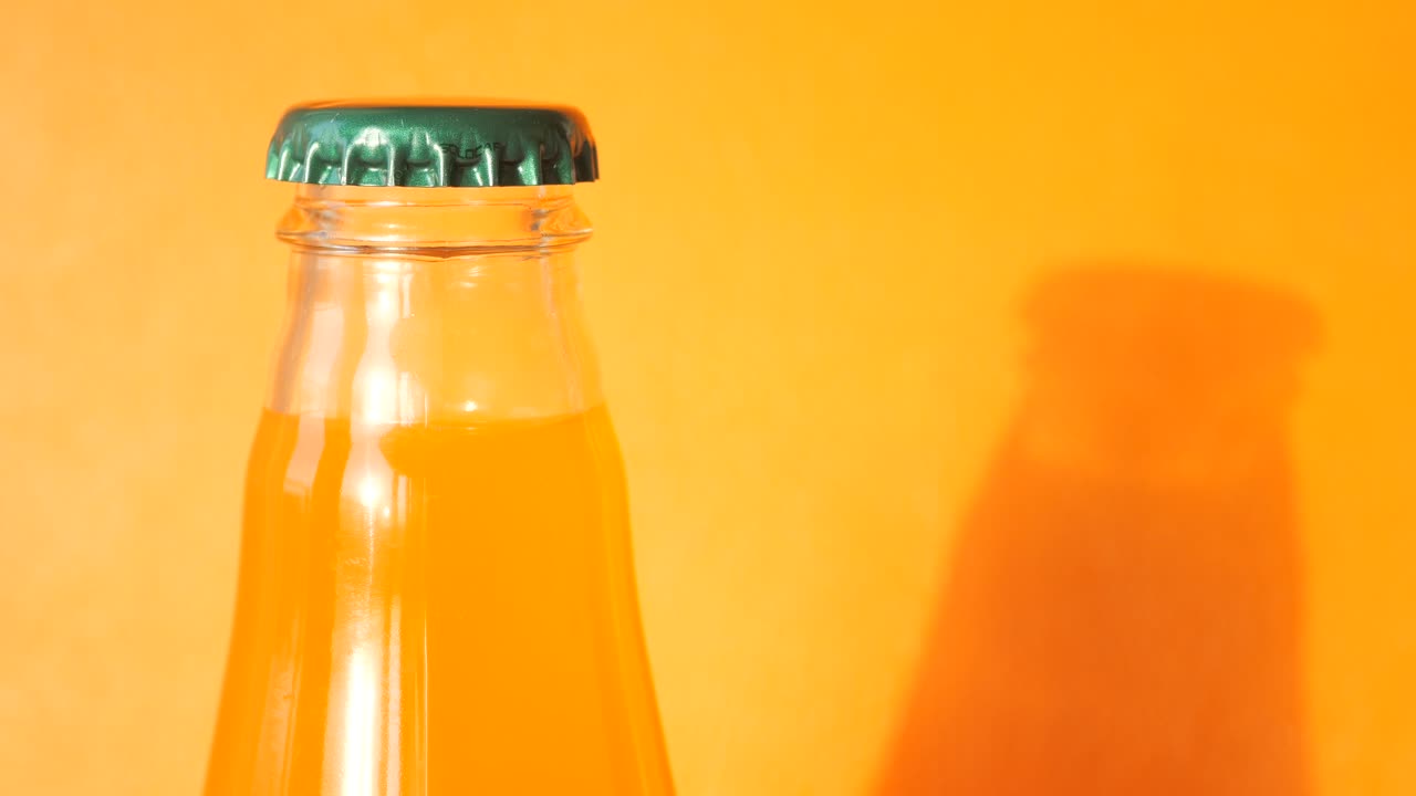 Orange Drink Bottle with Green Cap and Shadow on Orange Background