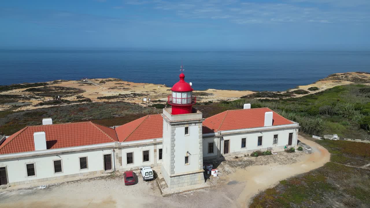 Aerial orbits Cabo Sardao lighthouse on rugged Portugal ocean coast