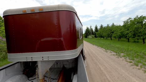 pulling horse trailer with pickup truck on gravel road, back pov