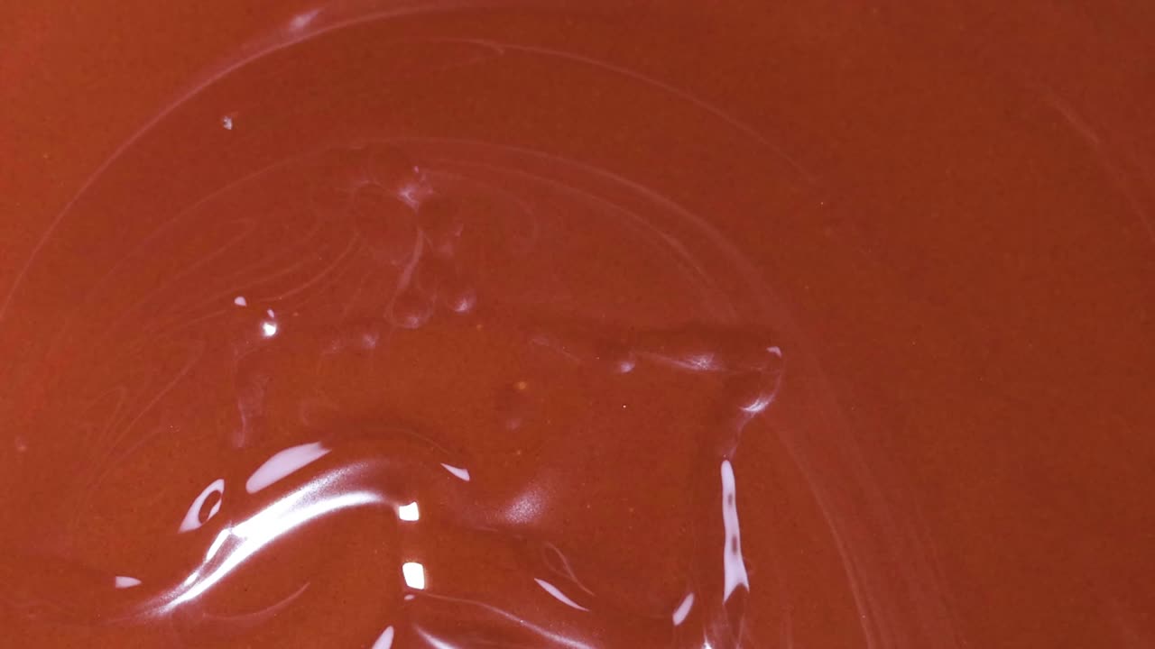 Primissimo piano di una fragola matura immersa in una pozza di cioccolato fuso e cremoso