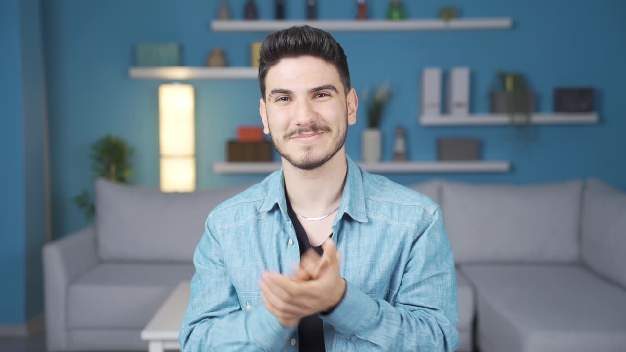 un joven satisfecho aplaudiendo, felicitando.