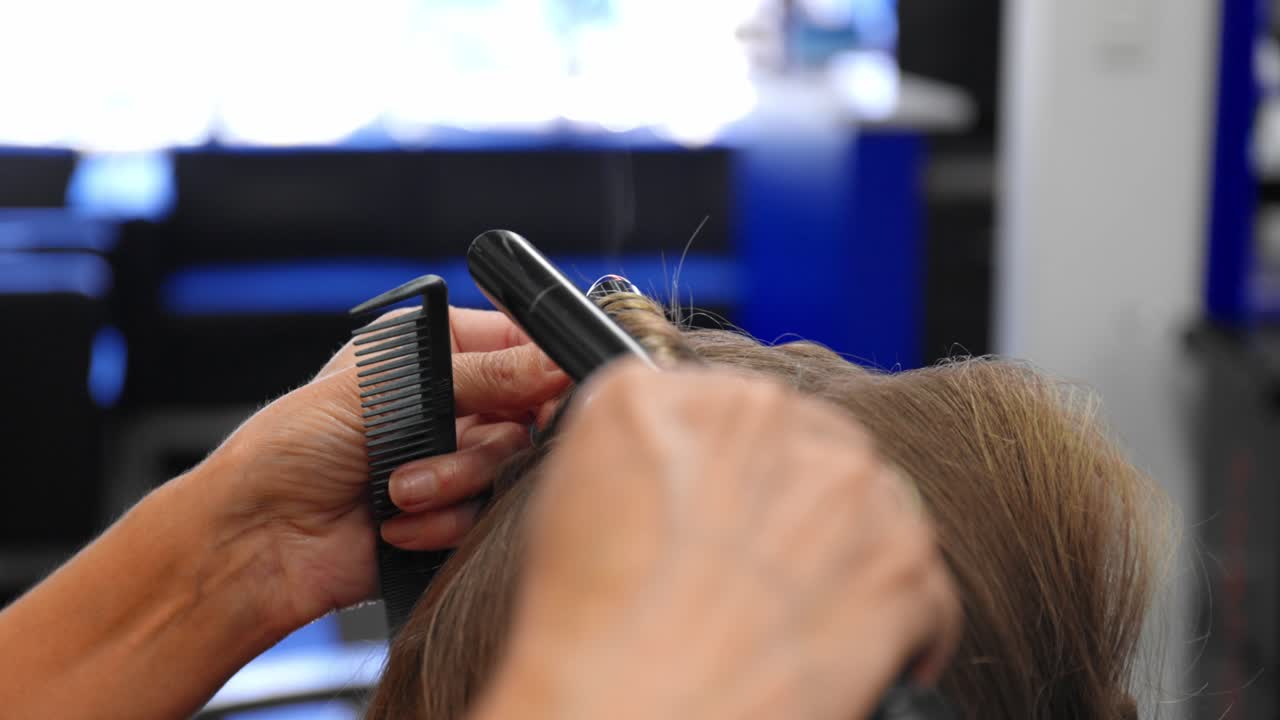 mujeres girando el cabello castaño en varitas rizadoras, luego sosteniendo, mientras sostienen un peine
