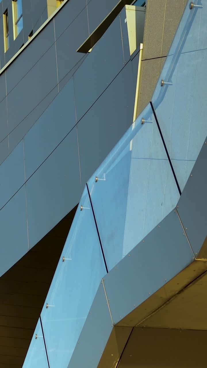 Primer plano de la barandilla de cristal y los paneles de aluminio de un edificio contemporáneo. Ideal para vídeos de diseño arquitectónico, desarrollo urbano y marketing inmobiliario.