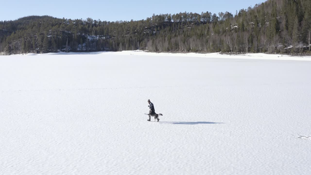hombre con su perro corriendo y jugando en el paisaje nevado durante el día