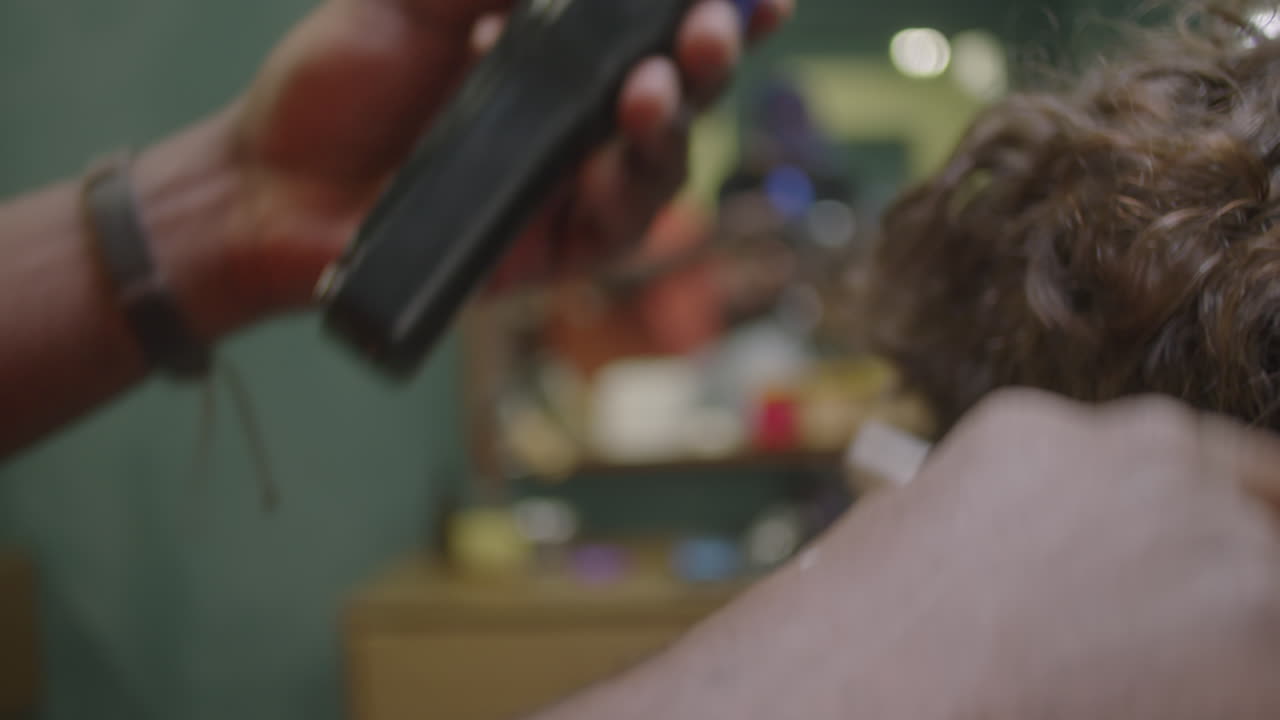 Hands of Barber Using Clippers for Trimming Neck Hair of Client