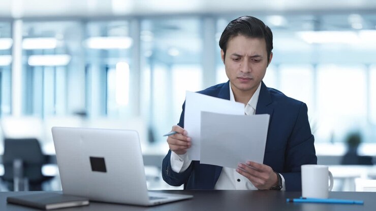 Indian manager reading and signing reports