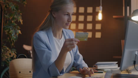 woman using credit card on computer in modern office