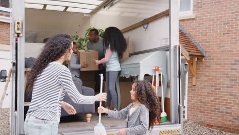 family unloading furniture from removal truck into new home