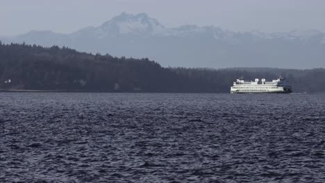 Anchorage,-ferry-crossing-bay-in-winter,-snowy-forest-and-mountains-in-distance