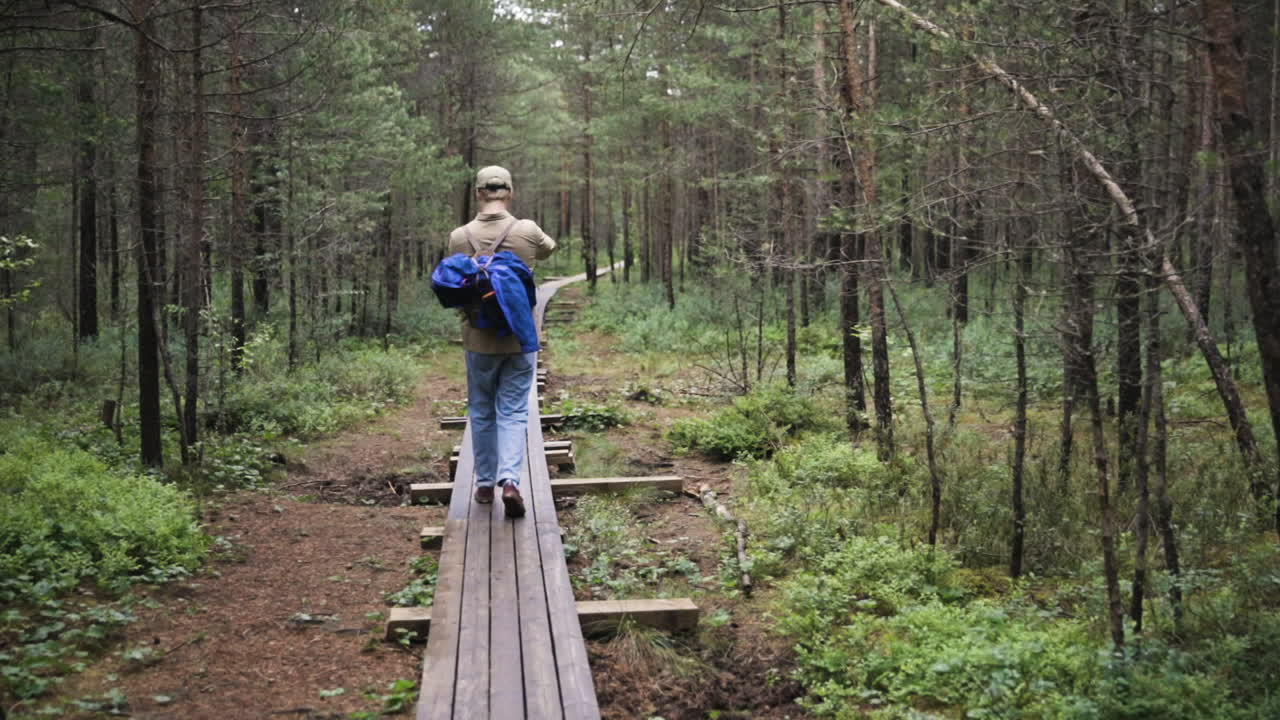 siga la foto de un hombre caminando por el bosque con una mochila