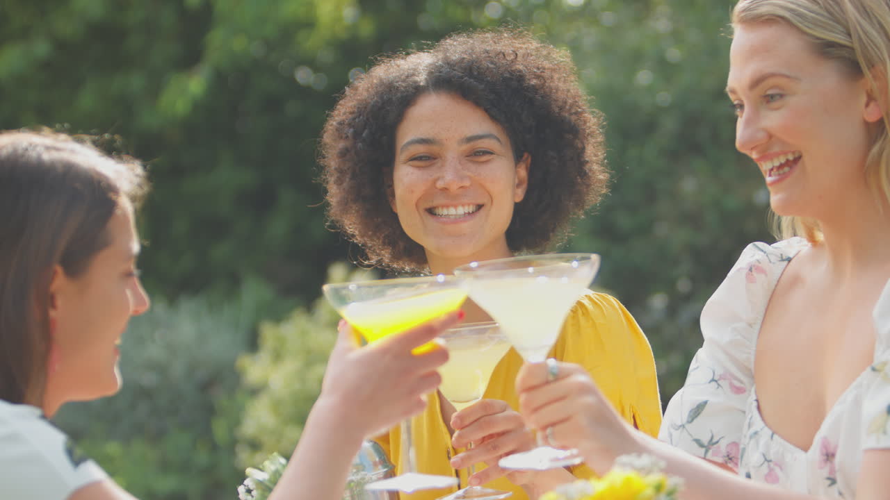 세 명의 여성 친구들이 테일을 는 집에서 여름 정원에서 야외에 앉아 있습니다.