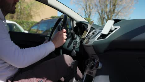 un joven apaga la ignición del coche, abre la puerta y sale del vehículo