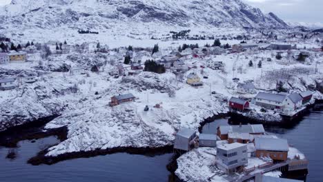 vista aérea del pacífico y pintoresco paisaje cubierto de nieve de lofoten con edificios esparcidos en la costa