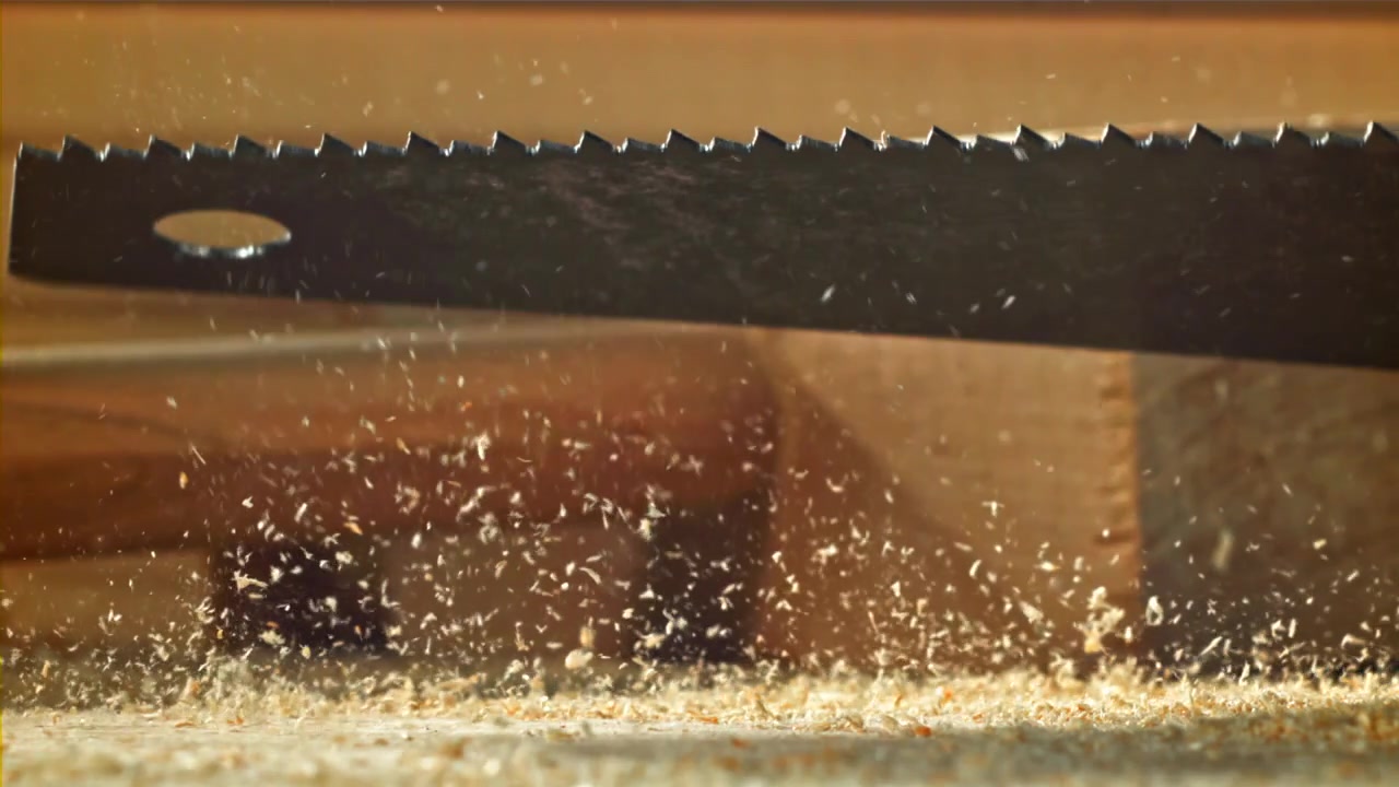 Nahaufnahme eines Sägeblatts, das Holz schneidet, mit umherfliegenden Sägespänen
