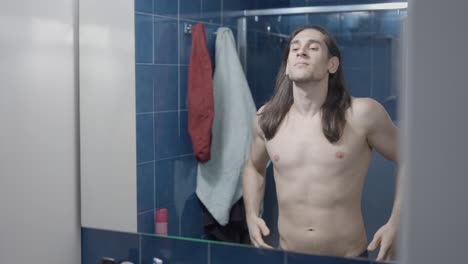 man checking his body in the bathroom mirror