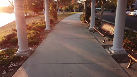 vibrant sunrise drone flight past park benches and pillars in southern california