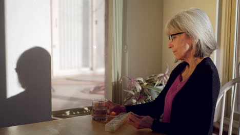 An-elderly-woman-taking-her-daily-prescription-medication-and-vitamin-pills-with-a-glass-of-water-then-smiling-with-good-health