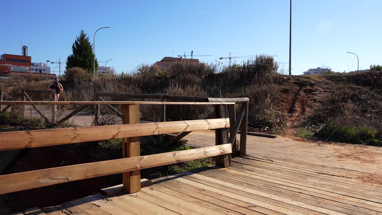 corredora mujer con auriculares cruzando un puente en el parque