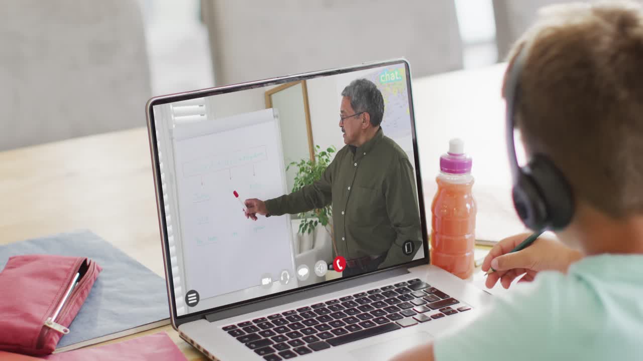 niño de escuela diverso teniendo clase en la llamada de video portátil con el maestro masculino en cámara lenta