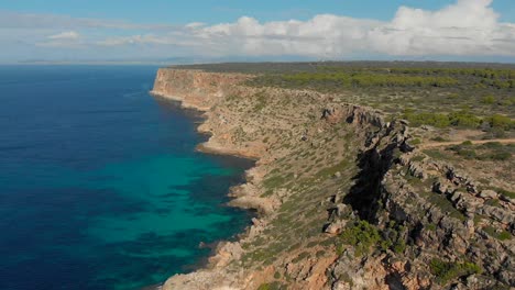 Drohnenaufnahmen-Fliegen-über-Den-Ozean-Zu-Den-Klippen-Mit-Blauem-Und-Türkisfarbenem-Wasser-Darunter