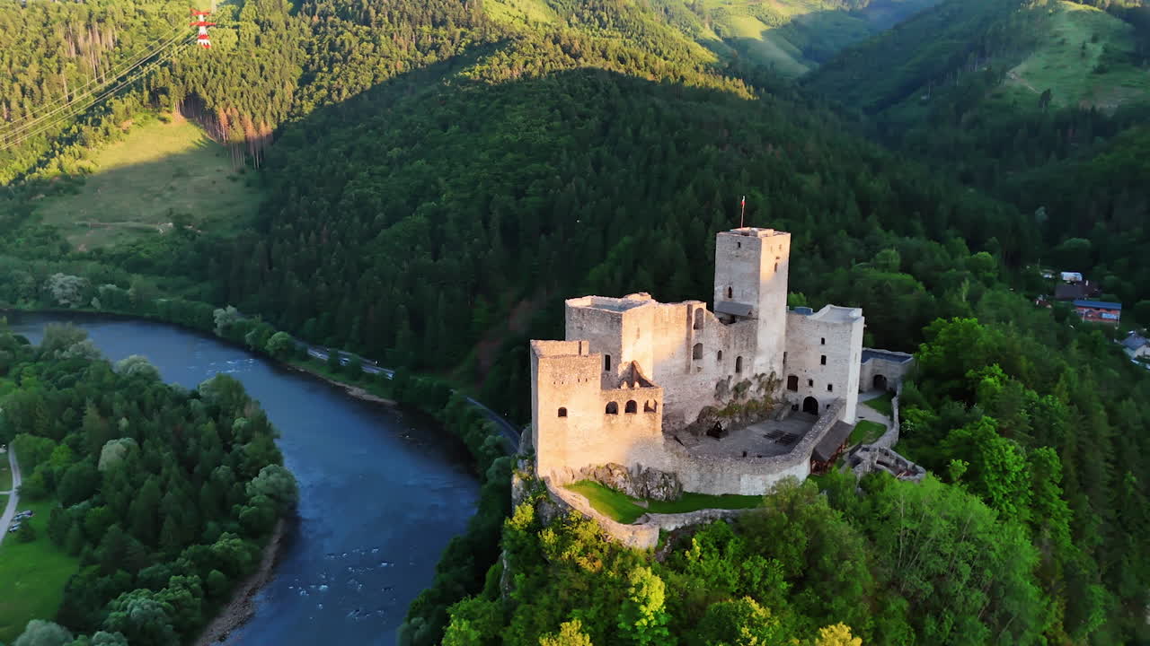 Flying around the Strecno Castle on the rock top. Village locating on the river waterfront at backdrop. Slovakia sightseeing