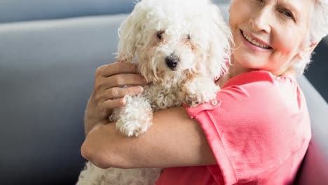 Happy-caucasian-senior-woman-holding-small-white-pet-dog-and-smiling