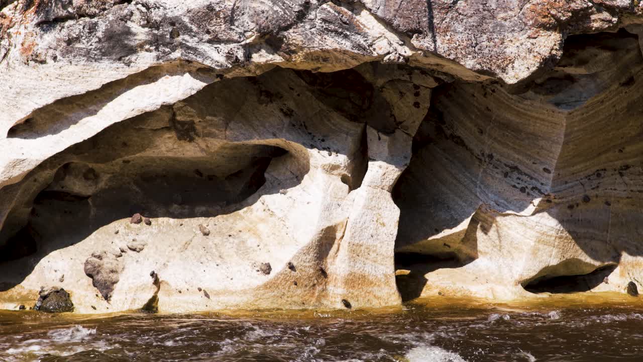The rocks on the banks of the river, eroded by the fast-flowing water