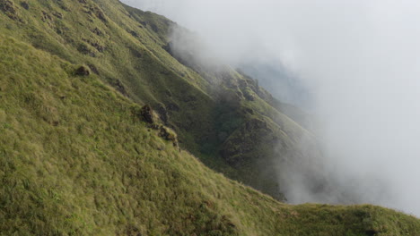 una vista de la empinada pradera alpina en las montañas del himalaya mientras la niebla y las nubes de la mañana barren el paisaje en la luz de la mañana