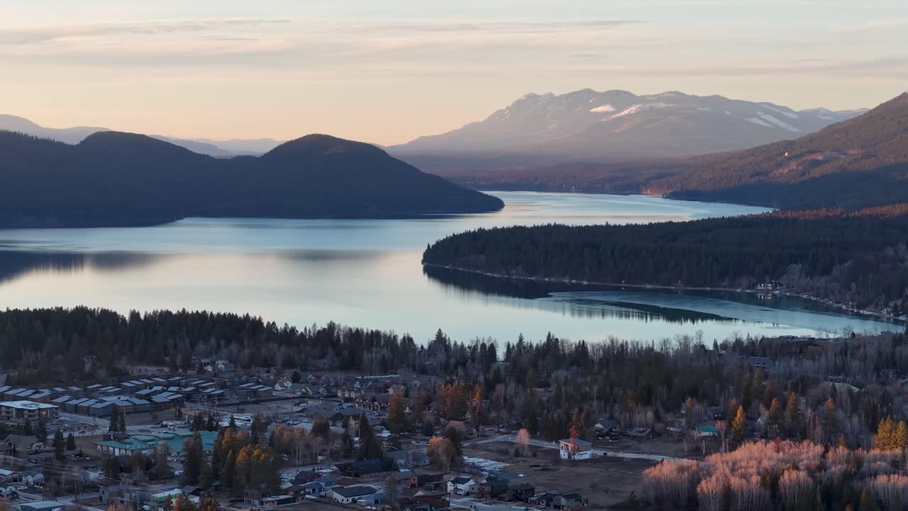 Splendida veduta aerea di Whitefish, Montana, vicino al Glacier National Park, che mostra il fiume Flathead e le aspre Montagne Rocciose, con un lago sereno e la città al tramonto.