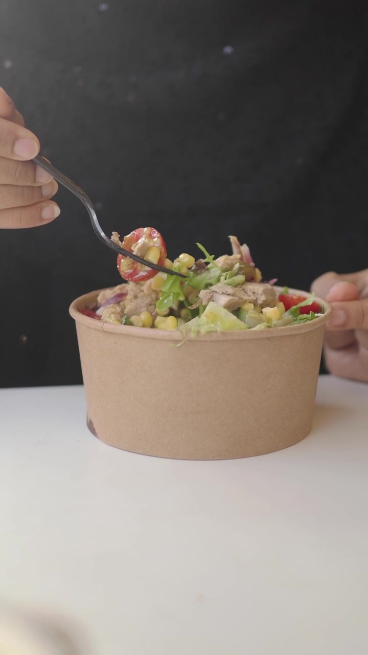 Person Eating Fresh Salad from a Paper Bowl