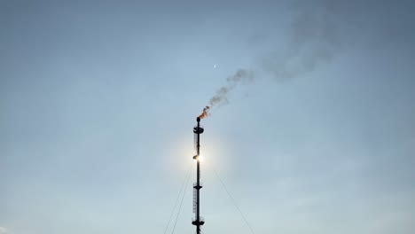 El-Sol-Brilla-Detrás-De-La-Torre-De-Bengalas-De-Gas-De-Refinería-Humeante-Contra-El-Cielo-Azul