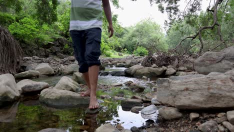 isolated man walking in natural river stream during morning