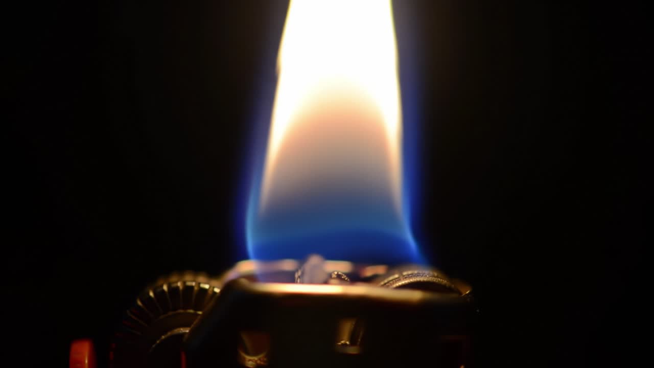 A Close-Up of a Flame from a Lighter Capturing the Intense Glow and Motion of Fire with a Deep Blue Hue in the Background, Emphasizing the Beauty of Flame Dynamics