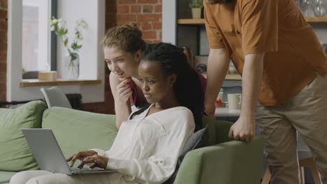 three  roommates looking something on laptop computer at home